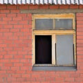 Old aged shed broken window glass, red bricks hut wall background, weathered grungy rusty dirty damaged wooden frame, textured Royalty Free Stock Photo