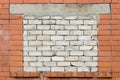 Old aged weathered red brick hut wall background, bricked-up shed window aperture bricked-in white damaged calcium silicate bricks