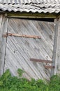 Old aged weathered wooden barn shack door, grey wood boarding hut wall planks, rusted metal hinges, rusty paint zinc texture