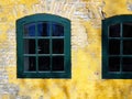 Old aged wooden window with cracked paint on a yellow painted wall Royalty Free Stock Photo