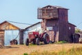 An old agricultural tractor stands in a collective farm yard waiting for work