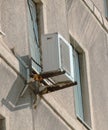 An old air conditioner near a window on the wall of a building