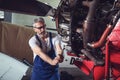 Aircraft mechanic repairs an aircraft engine in an airport hangar