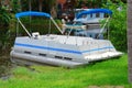 Old aluminum pontoon boat pulled up on shore Royalty Free Stock Photo