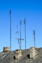 Old analog television antennas of meter and decimeter ranges on the roof with three chimneys Royalty Free Stock Photo