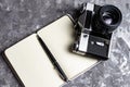 Old analogue camera and notepad. A clean notebook with a fountain pen and a retro camera on the table. Royalty Free Stock Photo