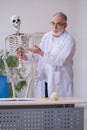 Old male anatomy teacher demonstrating human skeleton