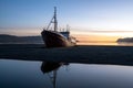 Old ancient, destroyed and abandoned norwegian whaling ship laying ashore in the westfjords of Iceland during sunset.