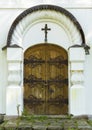 Old ancient gothic wooden church door with metal ornaments and cross on it