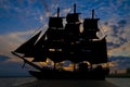 Old ancient pirate ship silhouette on peaceful ocean at sunset background