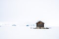 A old and ancient wooden cabin outdoors in beautiful snow covered mountains and foggy scenery with cross coutry skiiers