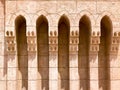 An old ancient yellow stone strong wall with arches in patterns and columns in an Arab Muslim Islamic warm tropical country in the