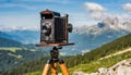 old antique bellows film camera on wooden tripod taking picture of landscape, outdoors photography, close up side rear view of Royalty Free Stock Photo