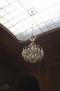 An old antique chandelier hanging from a glass roof in a lined interior