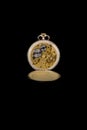 Old antique mechanical golden steel pocket watch with open lid isolated on black background.