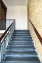 An old antique staircase in a historic building. An empty staircase and brick walls. Cast iron railings framed by wood Royalty Free Stock Photo