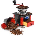 Old antique wooden black and red coffee grinder, cup, silver spoon and spilled coffee beans. Royalty Free Stock Photo