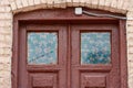 An old antique wooden door with small windows decorated with colorful mosaics. Painted wooden door on an old brick house