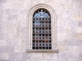 Old arced window with cast iron grill and white stone blocks frame front view Royalty Free Stock Photo