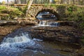 Old arch bridge a creek with waterfalls Royalty Free Stock Photo