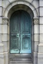 Old, arch, teal iron door to a tomb with ornaments. Door with steps inside the wall Royalty Free Stock Photo