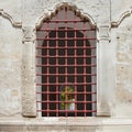 Old arch window with metal grid in a stone wall Royalty Free Stock Photo