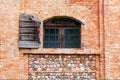 Old arched window with closed panes and open wooden balconies on abandoned stone and brick house facade. Royalty Free Stock Photo