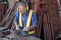 An old Asian carpenter is working to order in his own wood factory. With peace of mind by using hand tools including saws, wood Royalty Free Stock Photo