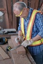 An old Asian carpenter is working to order in his own wood factory. With peace of mind by using hand tools including saws, wood Royalty Free Stock Photo