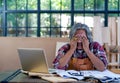 Old Asian craftsman act as feel bad or sad with something appear on laptop screen and sit in his workplace