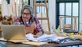 Old Asian craftsman act as feel happy with something appear on laptop screen and sit in his workplace