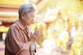 Old asian senior woman traveler tourist praying at buddhist temple Royalty Free Stock Photo