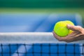 Old asian man hold two tennis balls in left hand, selective focus, blurred net and blue and green tennis court as backgroun Royalty Free Stock Photo