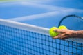 Old asian man hold two tennis balls in left hand, selective focus, blurred racket, net and green tennis court as background Royalty Free Stock Photo