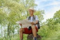 An old Asian man looks at a map of the hiking trails in a brochure. Royalty Free Stock Photo