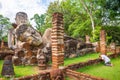 Old asian man pilgrim prostrating oneself in front of the big antique sitting and sleeping buddha in world heritage Kamphaeng Phet