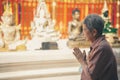 Old asian senior woman traveler tourist praying at buddhist temple Royalty Free Stock Photo