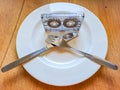 Old audio cassettes are lying on a white plate with cutlery on a wooden table Royalty Free Stock Photo