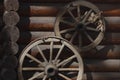an old, authentic, wooden cart wheel against a vintage brown wall. Royalty Free Stock Photo