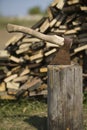 Old axe stuck in stump near woodpile Royalty Free Stock Photo