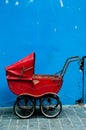 An old baby carriage against a blue wall