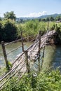 Old bamboo bridge is crossing the small river Royalty Free Stock Photo