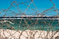 Old barbed wire infront of sea. Wire and blue sky with clouds. Safety fence of barbed wire against the blue sky and sea Royalty Free Stock Photo