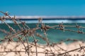 Old barbed wire infront of sea. Wire and blue sky with clouds. Safety fence of barbed wire against the blue sky and sea Royalty Free Stock Photo