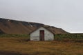 Old barn in a field surrounded by hills under a cloudy sky in Iceland Royalty Free Stock Photo