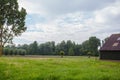 An old barn in a green field next to a forest and hill. Image taken on a partly cloudy day and has a vintage effect applied. Royalty Free Stock Photo