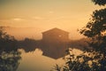 Old barn on lake shore on misty sunrise Royalty Free Stock Photo