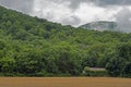 An old barn sits under green mountains and fog.