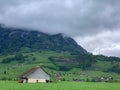 an old barn sitting on the top of a lush green hillside