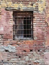 An old barred window sits in a dilapidated brick wall, layers of history peeling away. The stark contrast of the Royalty Free Stock Photo